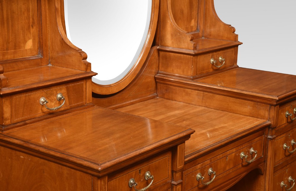 An Edwardian mahogany inlaid dressing table featuring a central oval mirror, upper trinket drawers, and twin pedestals with brass handles. View IX
