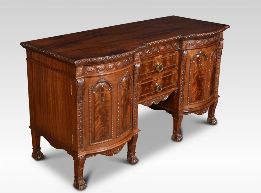 A deep brown mahogany inverted breakfront sideboard featuring carved accents, flame mahogany door panels, two central drawers, and carved claw-and-ball feet. View III