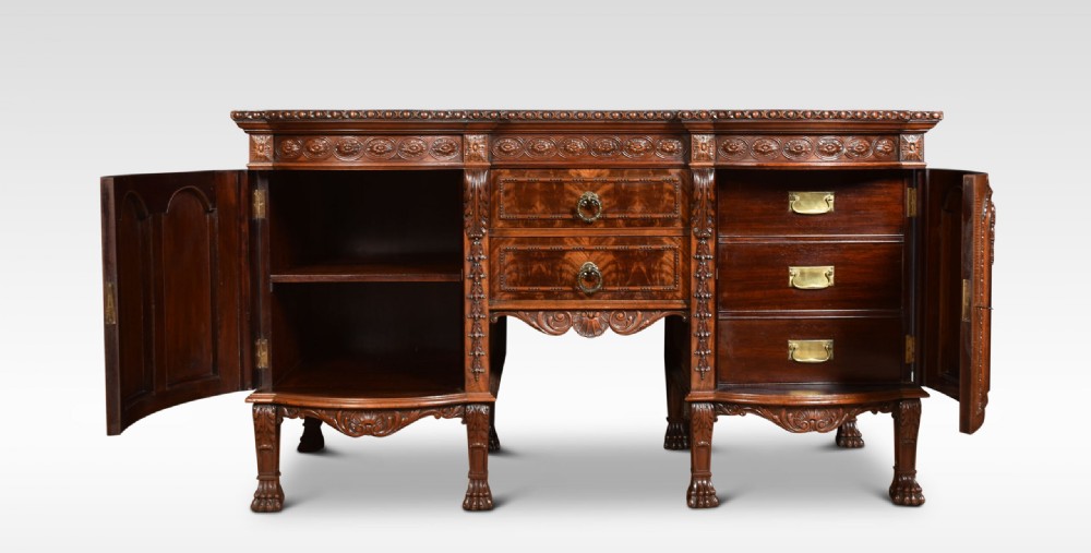 A deep brown mahogany inverted breakfront sideboard featuring carved accents, flame mahogany door panels, two central drawers, and carved claw-and-ball feet. View V