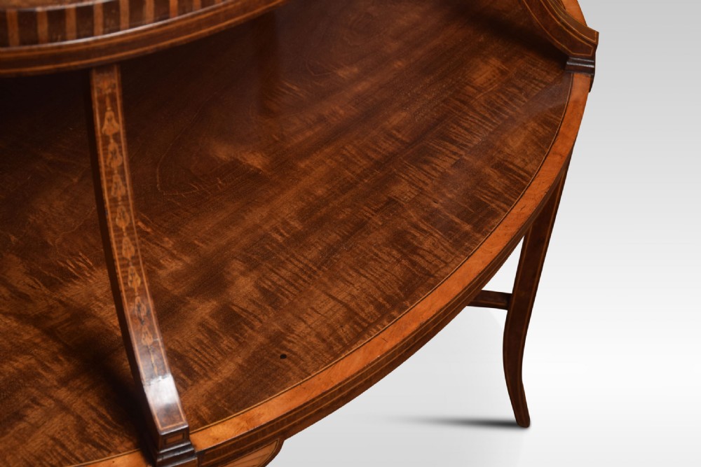 An oval two-tiered mahogany etagere table featuring satinwood crossbanded borders, fan inlays, sweeping upper supports, and twin brass handles on the top shelf. View VI