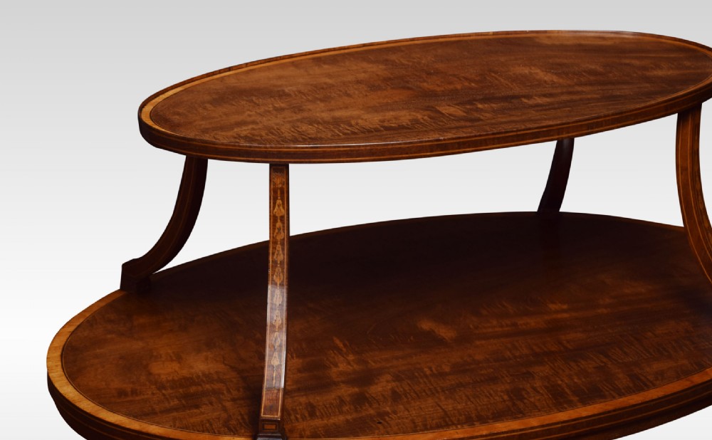 An oval two-tiered mahogany etagere table featuring satinwood crossbanded borders, fan inlays, sweeping upper supports, and twin brass handles on the top shelf. View VII