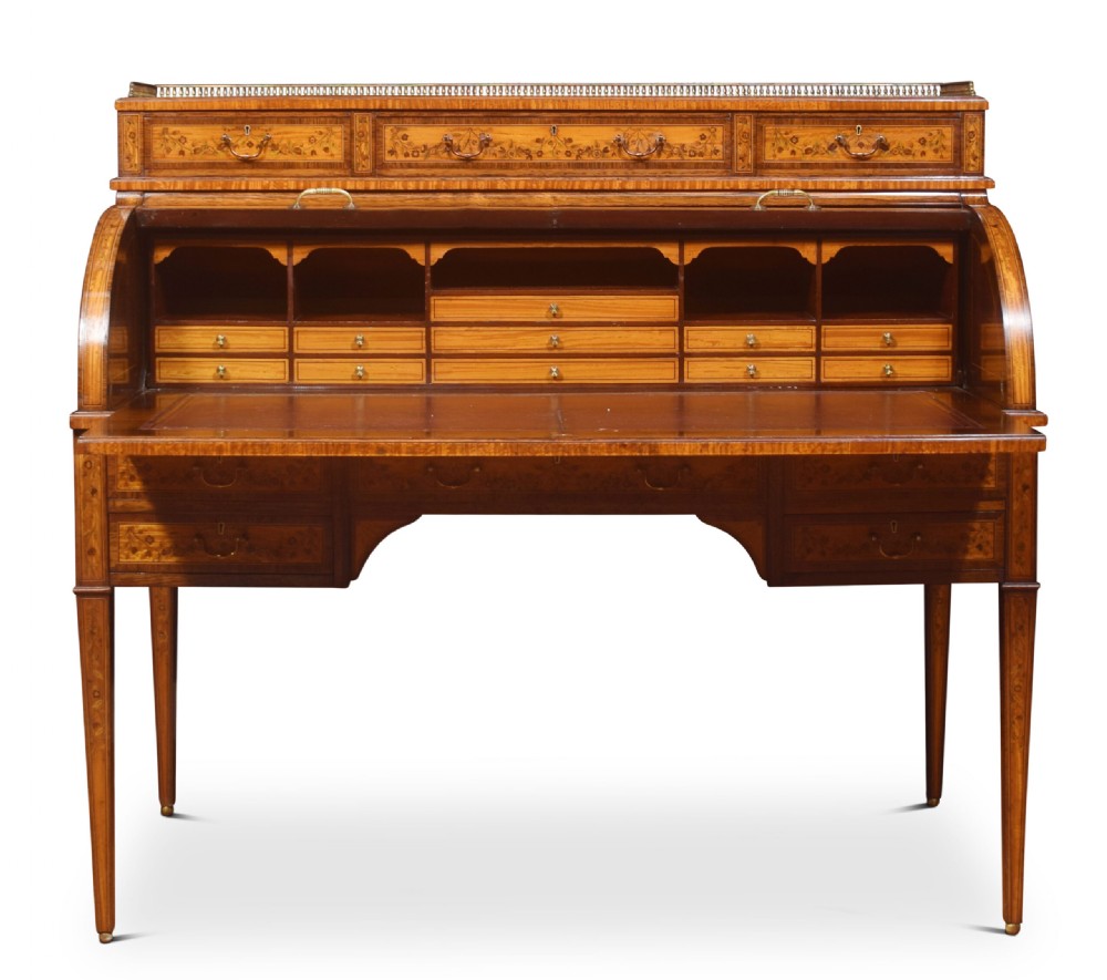 A Sheraton Revival satinwood cylinder bureau featuring detailed floral marquetry inlays, a curved roll-top front, brass gallery, and multiple drawers raised on tapered square legs. View VIII