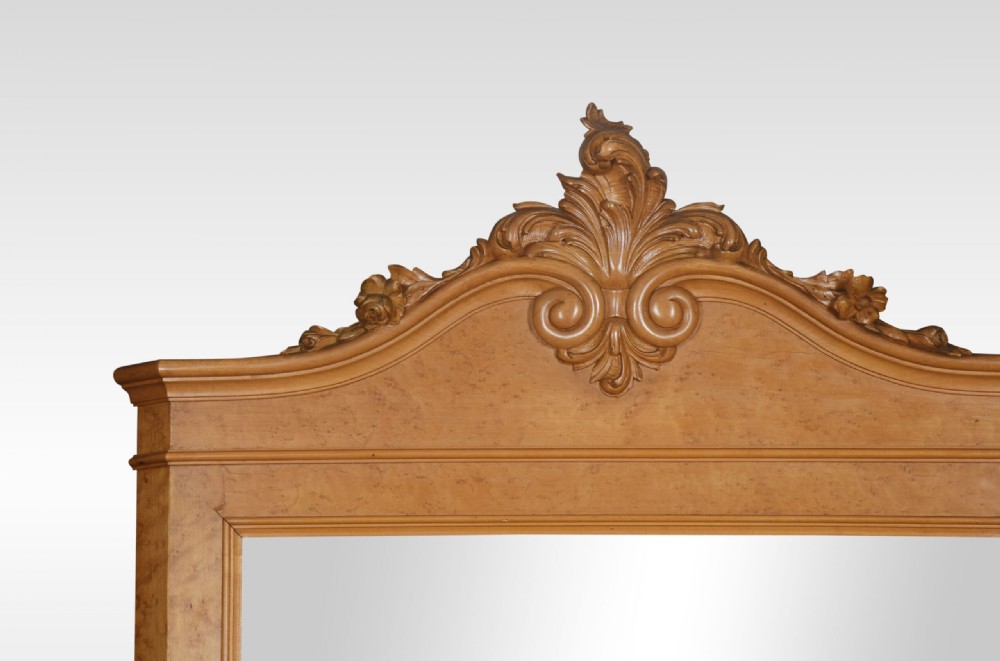 An antique birds eye maple chest of four drawers featuring a marble top, ornate brass handles, and a large arched mirror framed by a carved foliate crest. View II