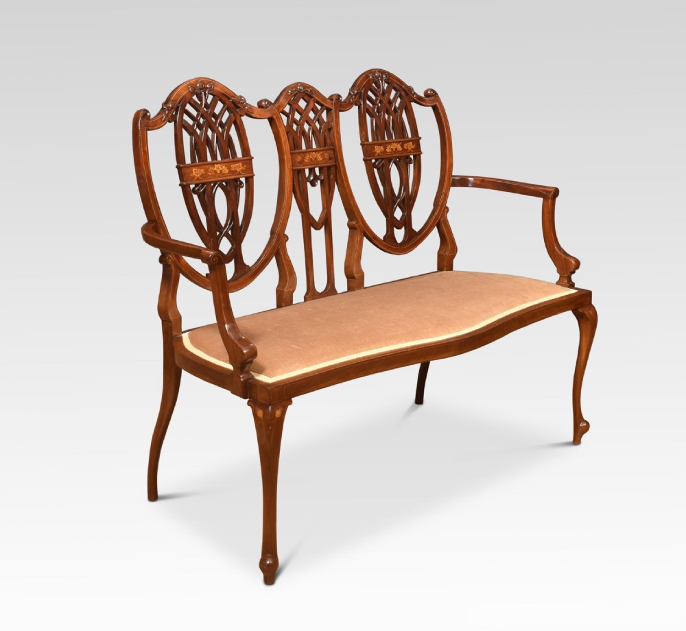 An Edwardian inlaid mahogany settee featuring a triple shield-back design with openwork lattice fretwork, floral marquetry, curved arms, and an upholstered seat. View II