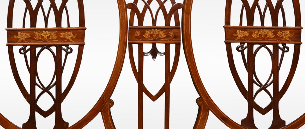 An Edwardian inlaid mahogany settee featuring a triple shield-back design with openwork lattice fretwork, floral marquetry, curved arms, and an upholstered seat. View III