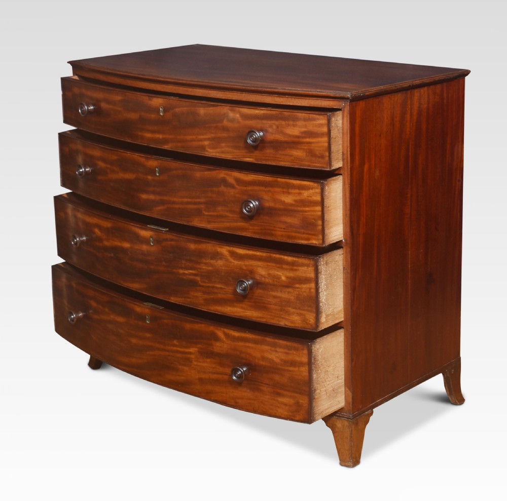 An antique Regency flame mahogany chest featuring four curved bow-front drawers with turned wooden knobs and splayed bracket feet. View VI