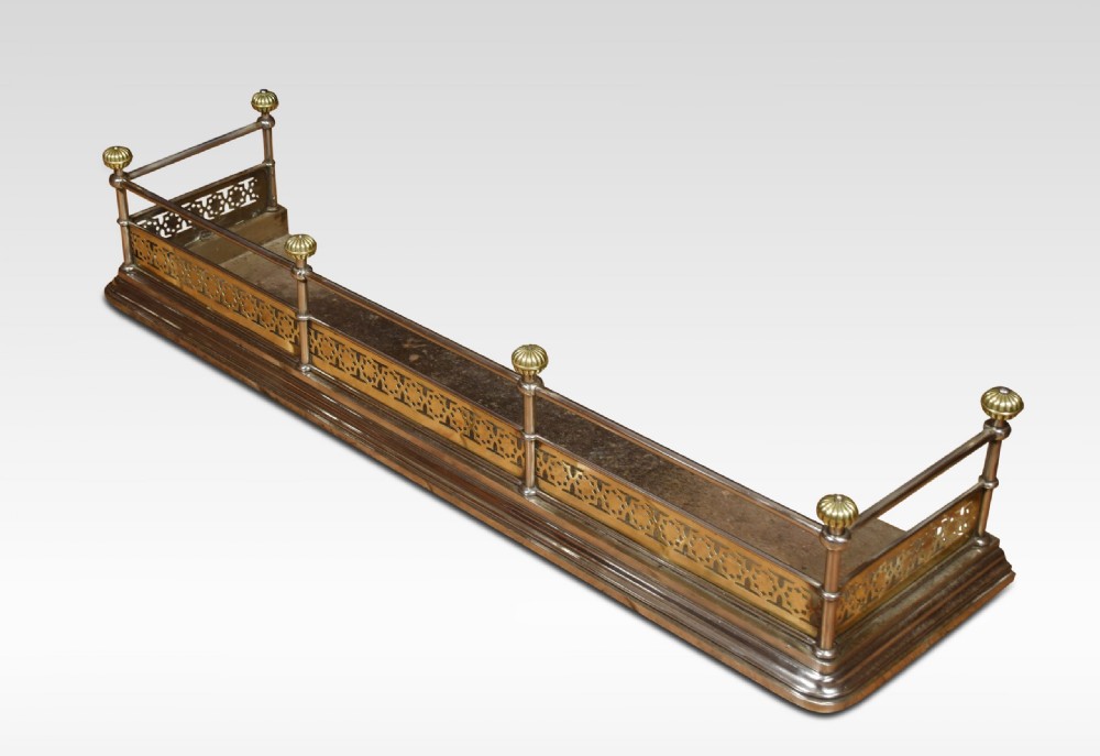 A Georgian polished steel and brass fireplace fender featuring a pierced geometric band, upper rail, and fluted brass finials. View IV