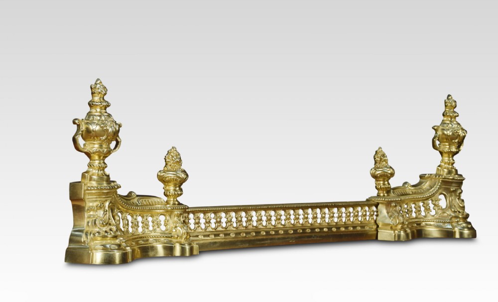 A 19th-century French adjustable gilt-brass fireplace fender featuring twin urn finials and pierced scrollwork.
