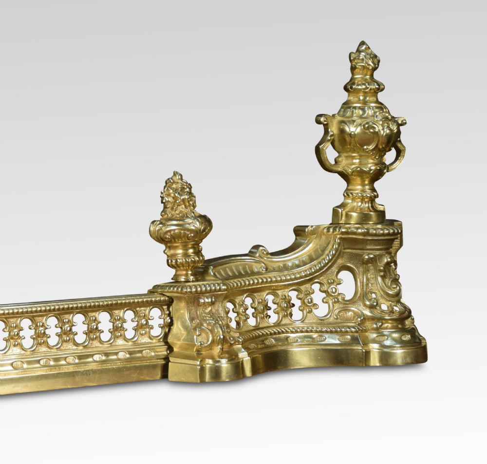 A 19th-century French adjustable gilt-brass fireplace fender featuring twin urn finials and pierced scrollwork. View V