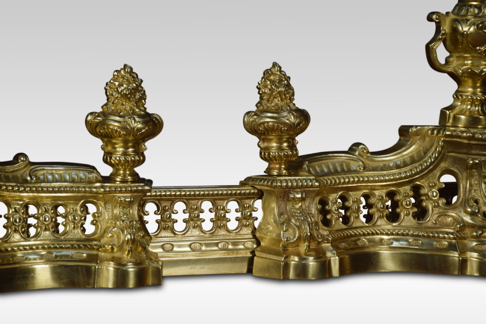 A 19th-century French adjustable gilt-brass fireplace fender featuring twin urn finials and pierced scrollwork. View VI