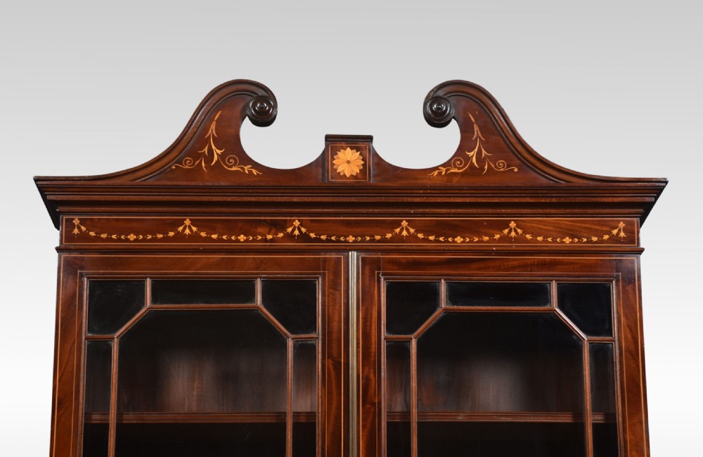 An antique mahogany bureau bookcase featuring a swan-neck pediment, glazed cabinet doors, a drop-down writing desk, and intricate floral marquetry inlay across the lower drawers. View II