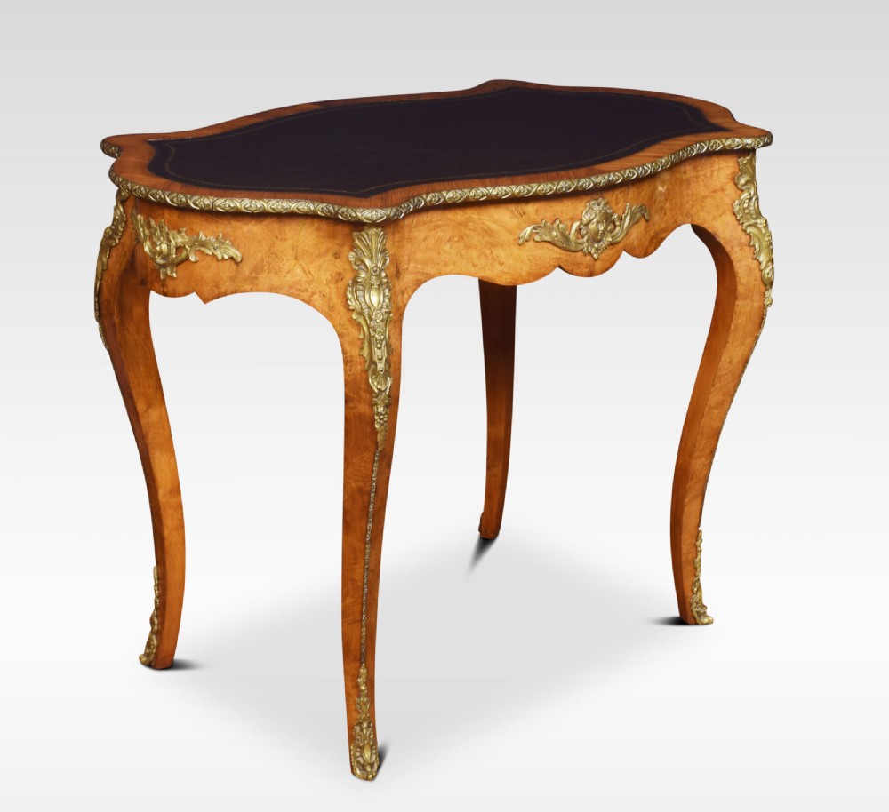 A 19th-century French Rococo style burr walnut writing table with cabriole legs, gilt-bronze mounts, and a dark leather inset top.
