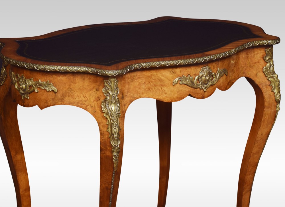 A 19th-century French Rococo style burr walnut writing table with cabriole legs, gilt-bronze mounts, and a dark leather inset top. View II