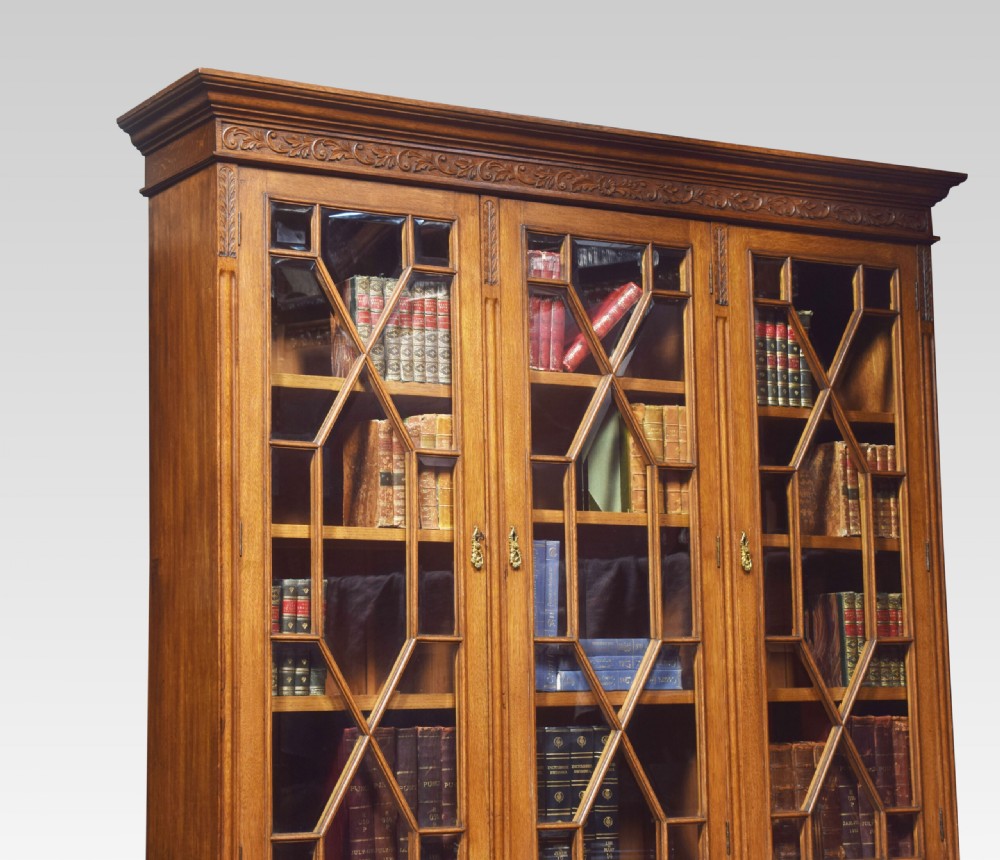 A large warm brown oak bookcase featuring three upper glazed doors with geometric astragal glazing, three drawers, and three panelled cupboard doors below. View VIII