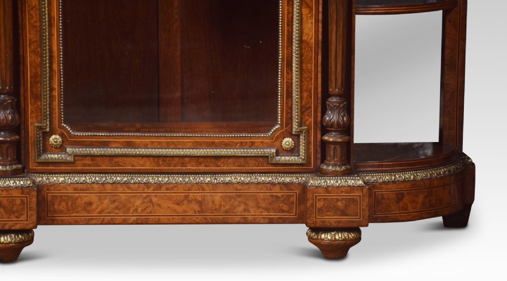 A nineteenth-century figured walnut credenza with a glazed central door, open mirrored side shelves, floral marquetry inlay, and gilt-bronze mounts. View II