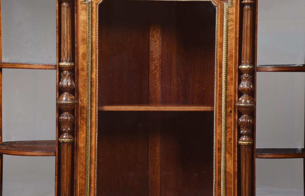 A nineteenth-century figured walnut credenza with a glazed central door, open mirrored side shelves, floral marquetry inlay, and gilt-bronze mounts. View VI