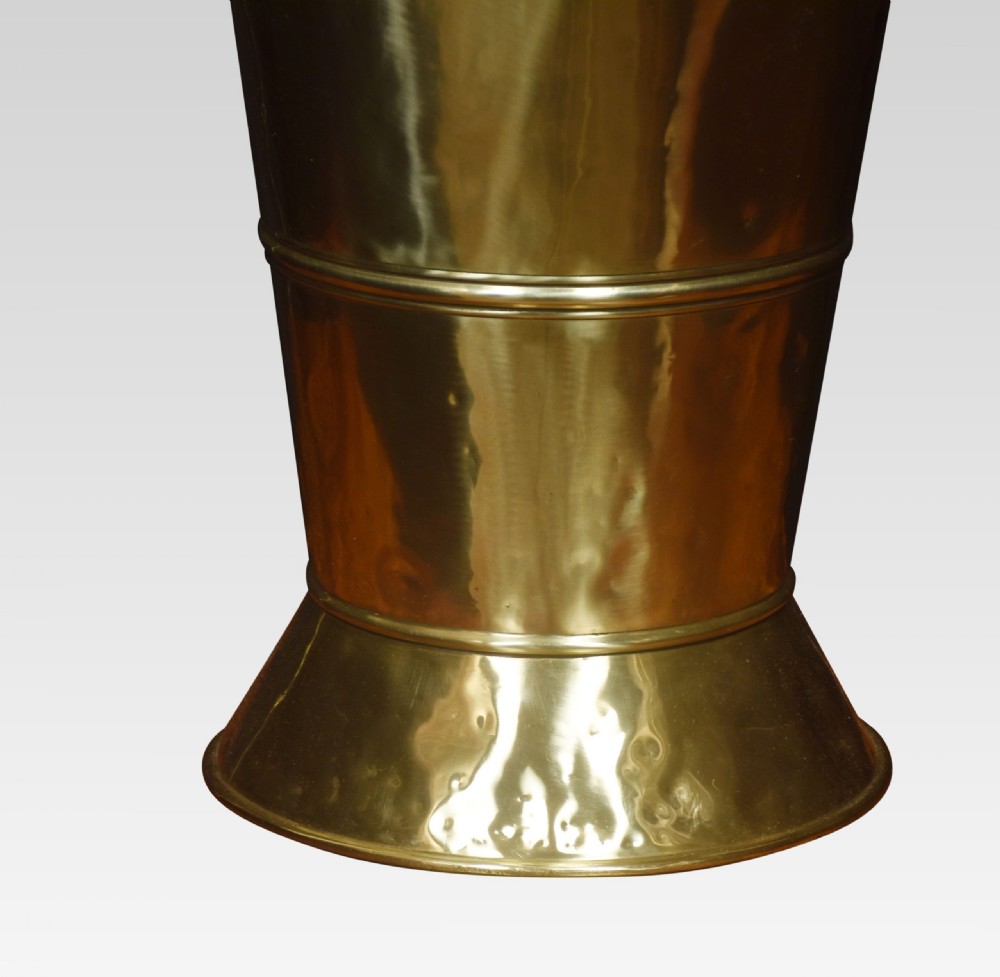 A tall 19th-century polished brass umbrella stand featuring a flared base, tapered cylindrical body, and a scooped hood top with repousse trim along the rim. View III