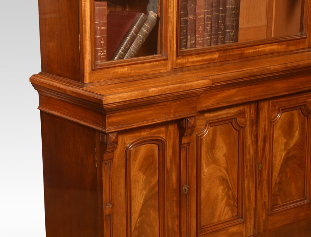 A large Victorian flame mahogany four-door breakfront library bookcase featuring arched glazed upper doors and panelled lower cupboard doors. View V