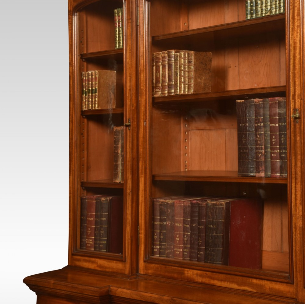 A large Victorian flame mahogany four-door breakfront library bookcase featuring arched glazed upper doors and panelled lower cupboard doors. View VIII
