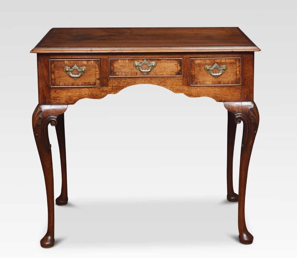An eighteenth-century Queen Anne walnut lowboy table with three drawers, brass drop handles, a shaped apron, and cabriole legs ending in pad feet.