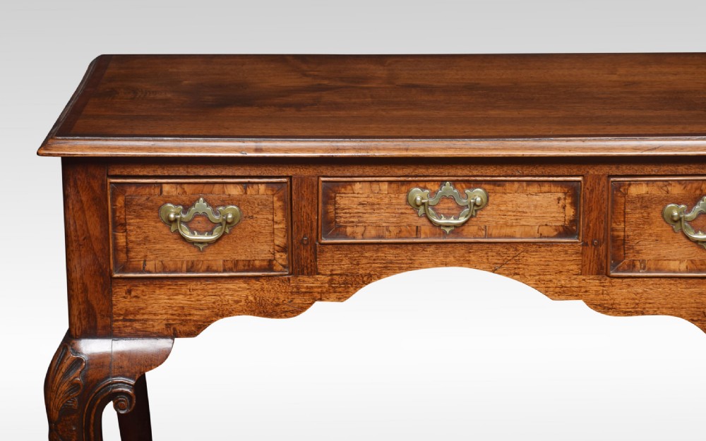 An eighteenth-century Queen Anne walnut lowboy table with three drawers, brass drop handles, a shaped apron, and cabriole legs ending in pad feet. View II