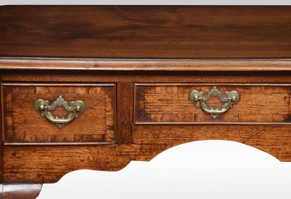 An eighteenth-century Queen Anne walnut lowboy table with three drawers, brass drop handles, a shaped apron, and cabriole legs ending in pad feet. View V