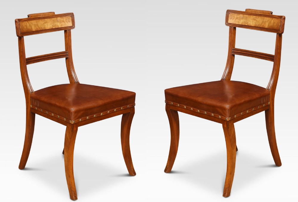 A set of eight Regency mahogany dining chairs featuring brown leather seats with brass stud detail, tablet top rails, and sabre legs. View VII