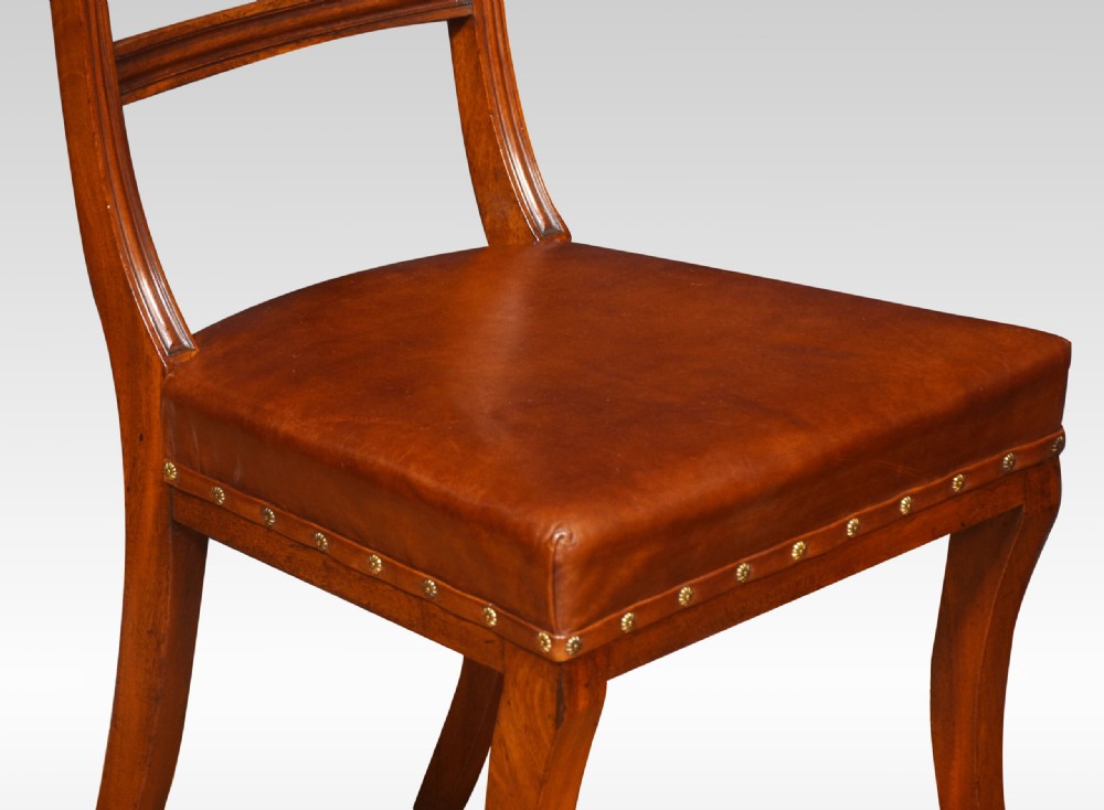 A set of eight Regency mahogany dining chairs featuring brown leather seats with brass stud detail, tablet top rails, and sabre legs. View IX