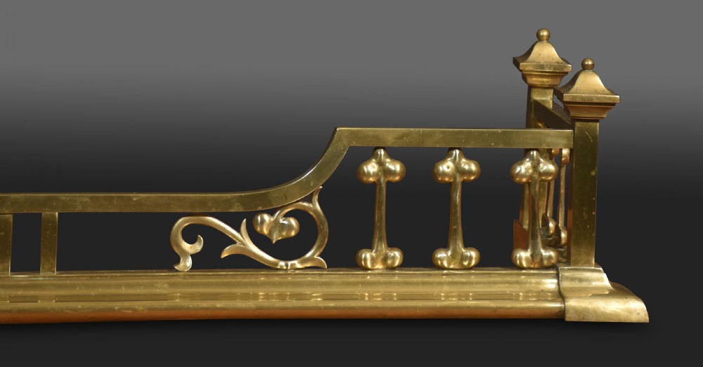 An antique solid brass Art Nouveau fireplace fender featuring stylized balusters, organic scrollwork motifs, and raised corner posts. View V