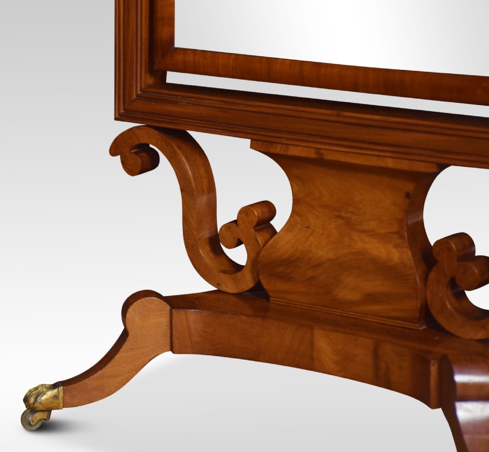 A Regency period mahogany cheval mirror featuring spiral-turned upright columns, finials, and a rectangular tilting frame resting on splayed legs with brass lion paw castors. View VII
