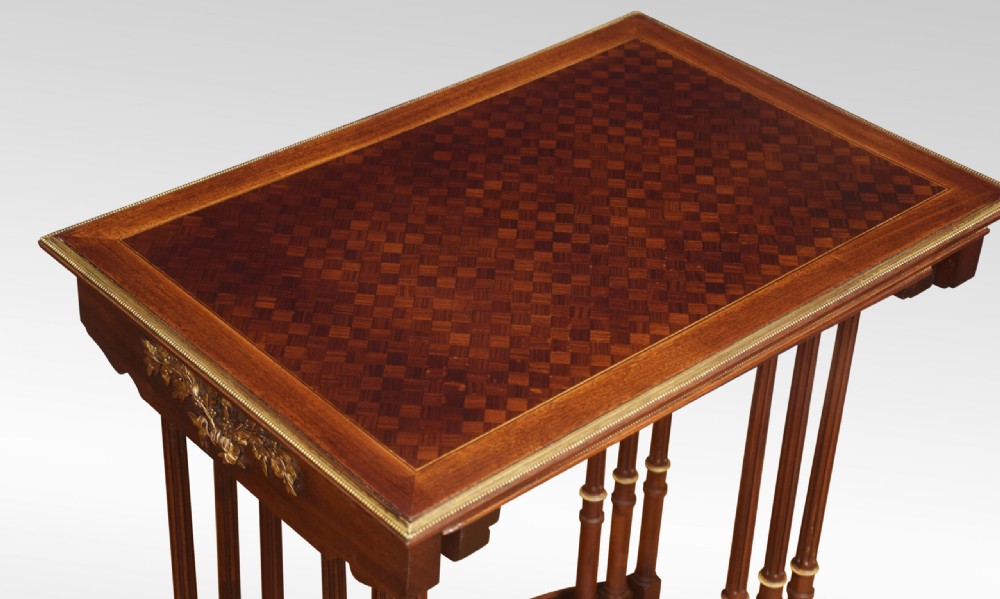 A set of three nesting walnut side tables featuring geometric parquetry tops, slender turned legs, and brass mounts. View IV