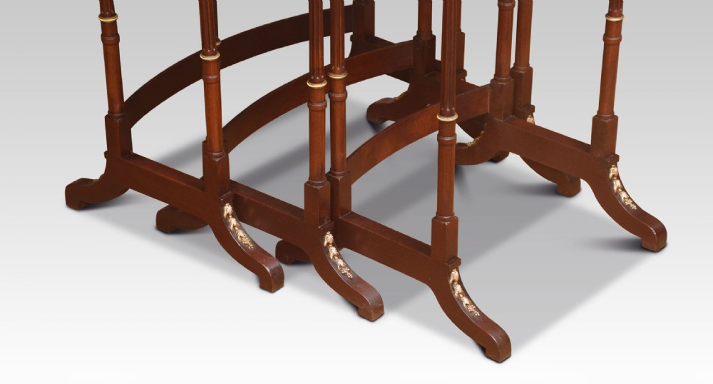 A set of three nesting walnut side tables featuring geometric parquetry tops, slender turned legs, and brass mounts. View VII