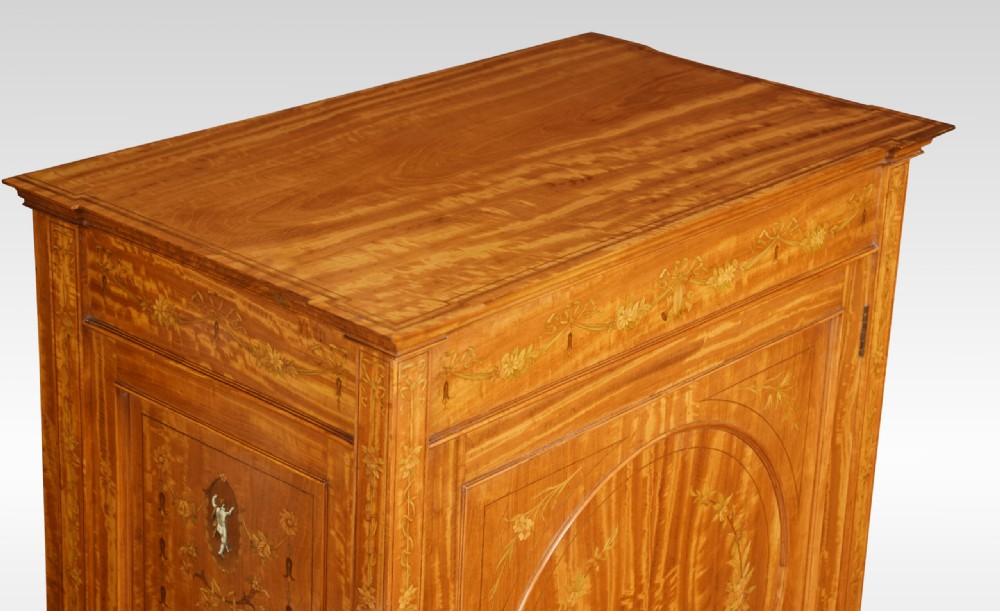 A late 19th-century satinwood side cabinet featuring intricate floral marquetry inlay, a central circular wreath medallion on a single panelled door, and square tapered legs. View VIII