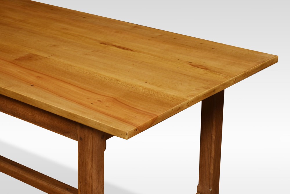 A large rectangular light brown wooden refectory dining table featuring two drawers along the front frieze and an H-stretcher base. View IV