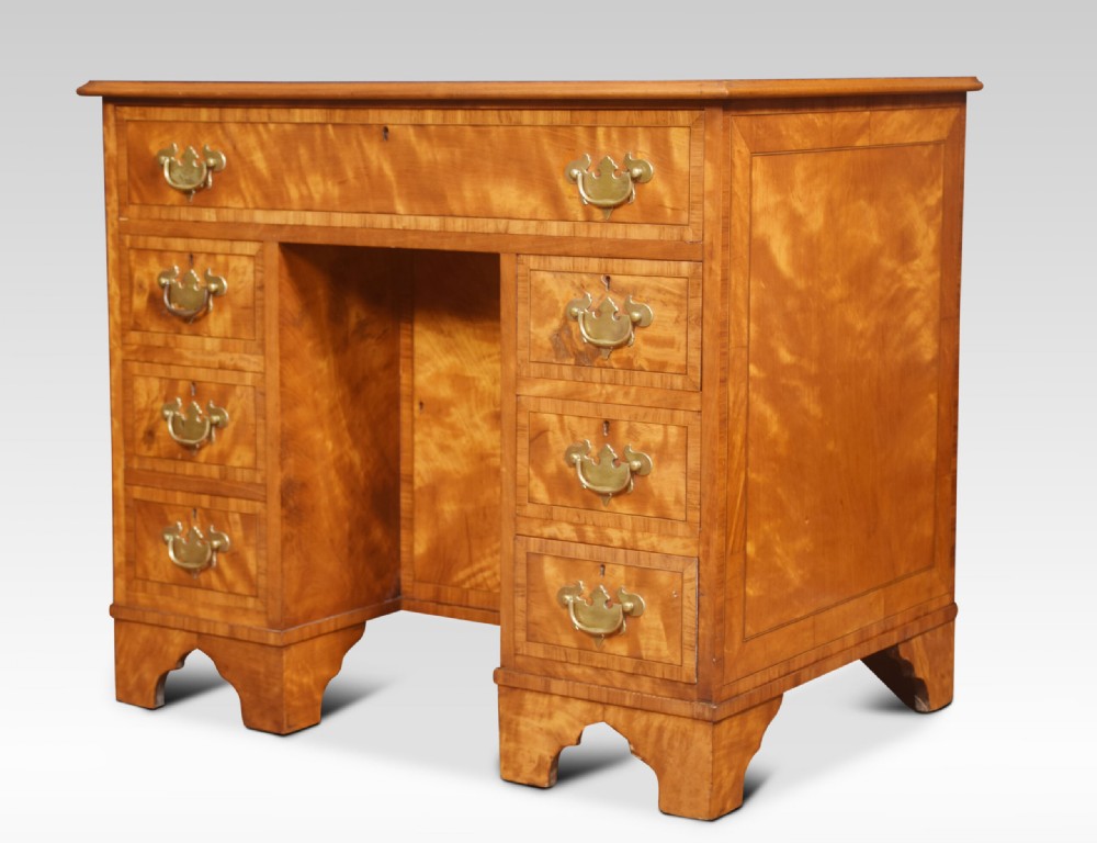 A George III style satinwood kneehole desk featuring crossbanded drawers, brass batwing handles, a central recessed cupboard, and bracket feet. View VI