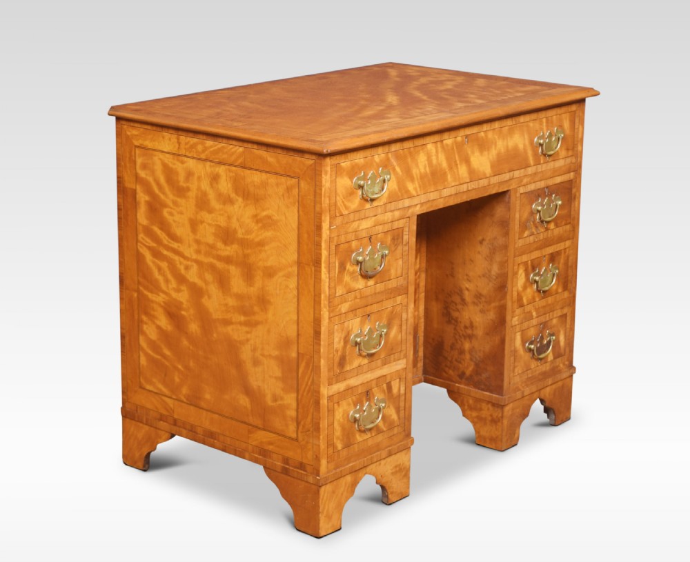 A George III style satinwood kneehole desk featuring crossbanded drawers, brass batwing handles, a central recessed cupboard, and bracket feet. View VIII