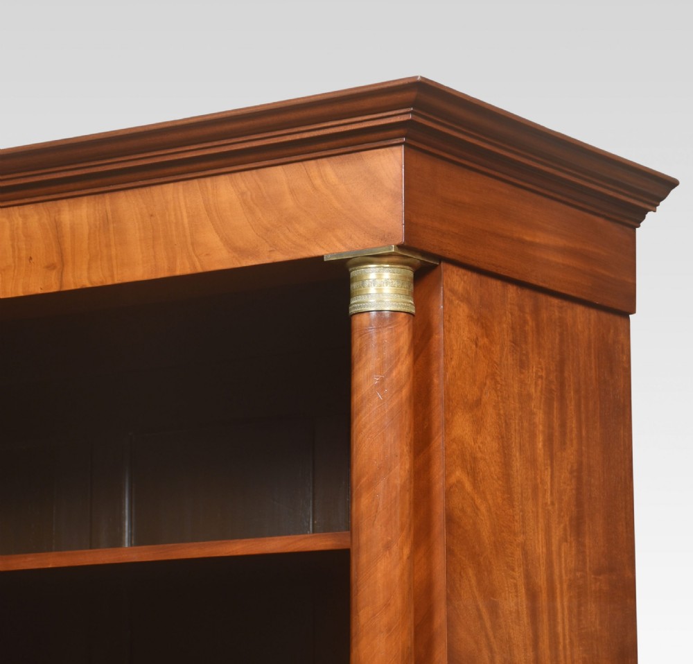 A tall open mahogany bookcase featuring classical flanking columns with brass capitals and adjustable interior shelving. View X