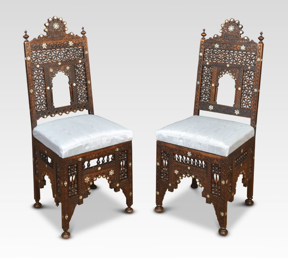 A pair of 19th-century carved dark hardwood Moorish side chairs with intricate mashrabiya fretwork, bone inlay, and pale silk upholstered seats. View II