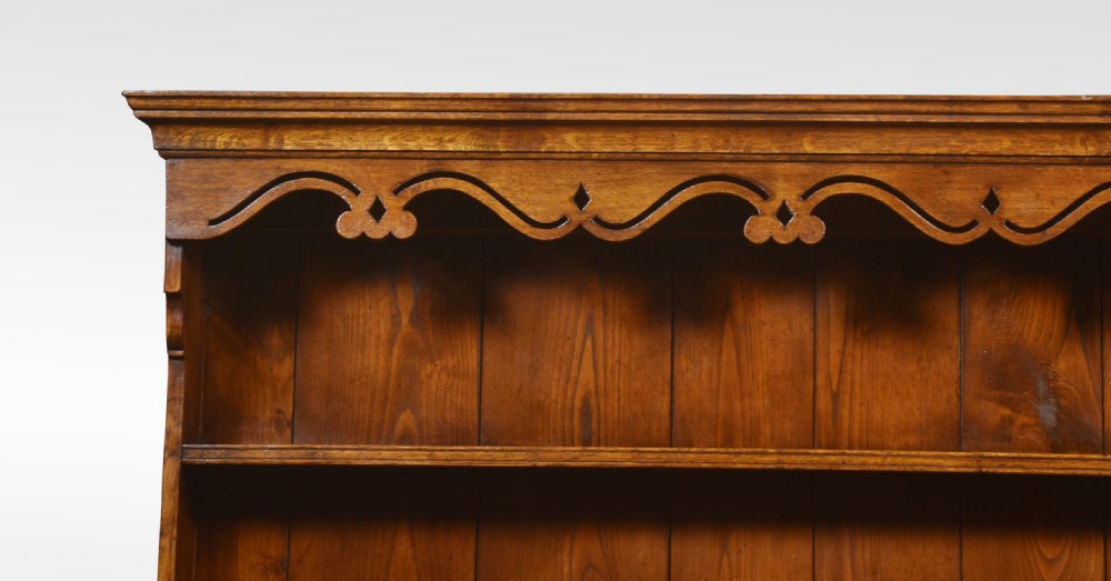 A warm brown Georgian style oak dresser featuring an upper open plate rack with a shaped frieze above three base drawers and cabriole legs. View III