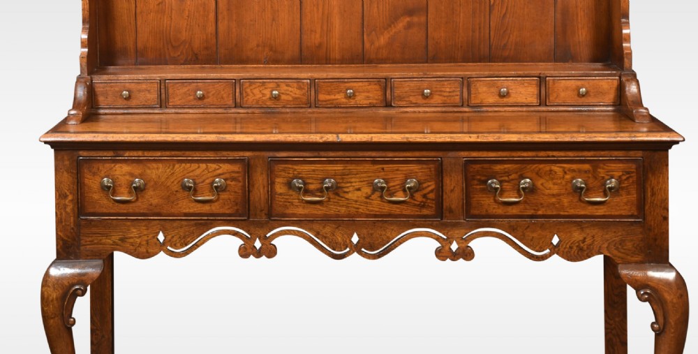 A warm brown Georgian style oak dresser featuring an upper open plate rack with a shaped frieze above three base drawers and cabriole legs. View VI