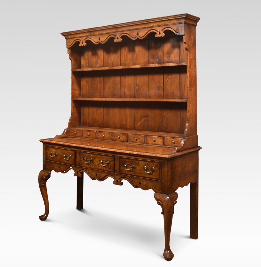 A warm brown Georgian style oak dresser featuring an upper open plate rack with a shaped frieze above three base drawers and cabriole legs. View VIII
