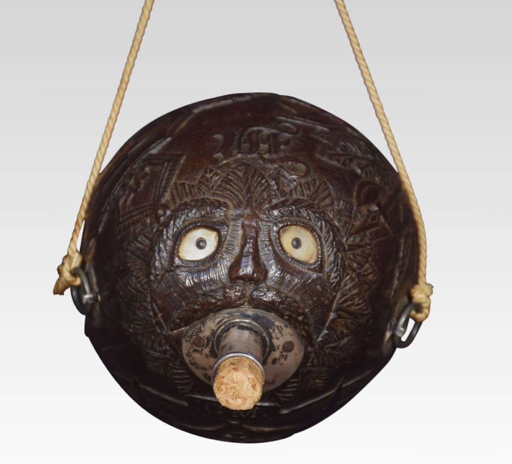 A 19th-century dark brown carved coconut flask featuring relief crests, an anchor motif, a metal neck with cork stopper, and suspension rope. View II