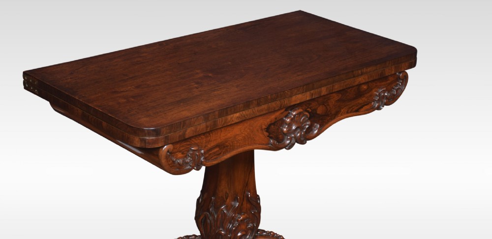 A Victorian dark rosewood fold-over card table featuring an ornate carved frieze, a central carved pedestal column, and carved scroll legs. View II