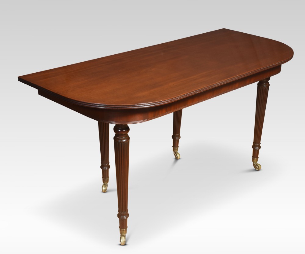 A large mahogany extending dining table featuring an imperial telescopic action, rounded corners, and reeded turned legs on brass castors. View XI