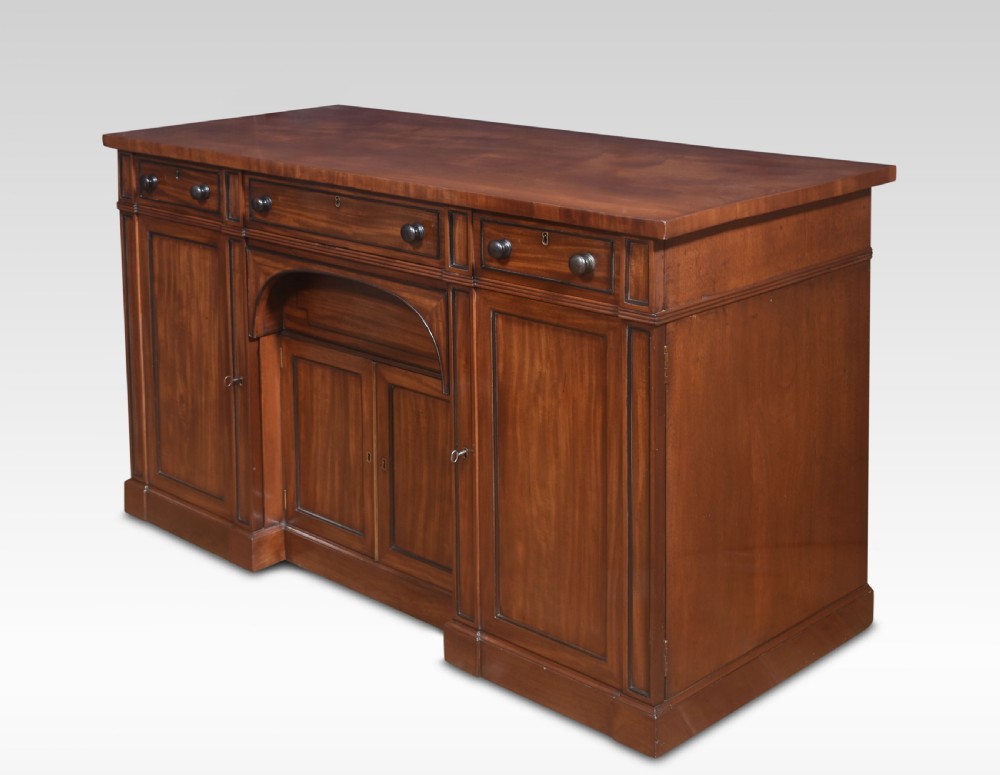 A Regency period warm brown mahogany sideboard featuring four cupboard doors, three top drawers, turned wooden knobs, and an arched central alcove. View VI