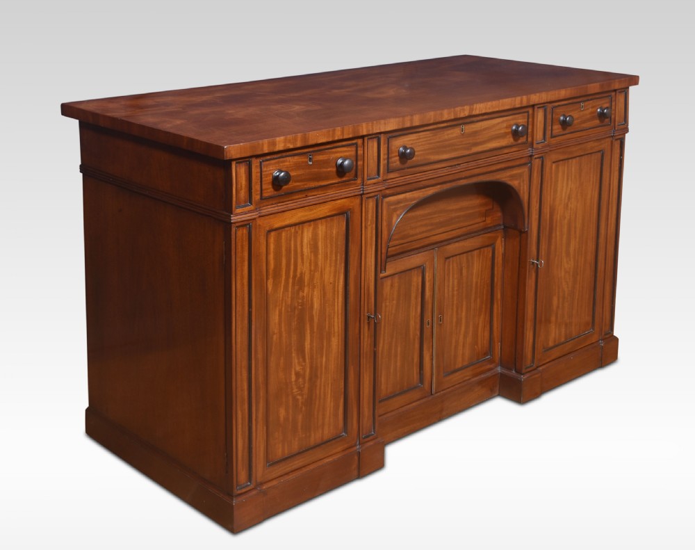 A Regency period warm brown mahogany sideboard featuring four cupboard doors, three top drawers, turned wooden knobs, and an arched central alcove. View VII