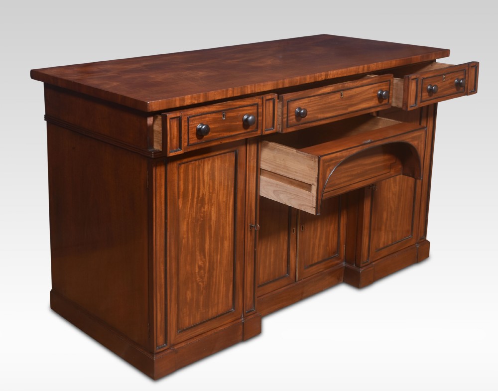 A Regency period warm brown mahogany sideboard featuring four cupboard doors, three top drawers, turned wooden knobs, and an arched central alcove. View X