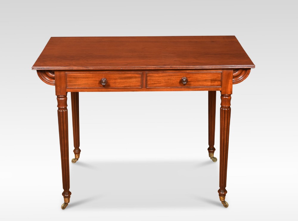 A mahogany writing table featuring two frieze drawers with turned wooden knobs, fluted turned legs, side scroll details, and brass castors.