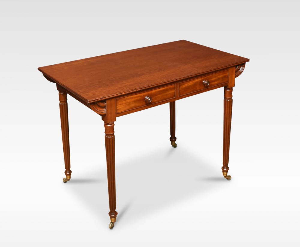 A mahogany writing table featuring two frieze drawers with turned wooden knobs, fluted turned legs, side scroll details, and brass castors. View III