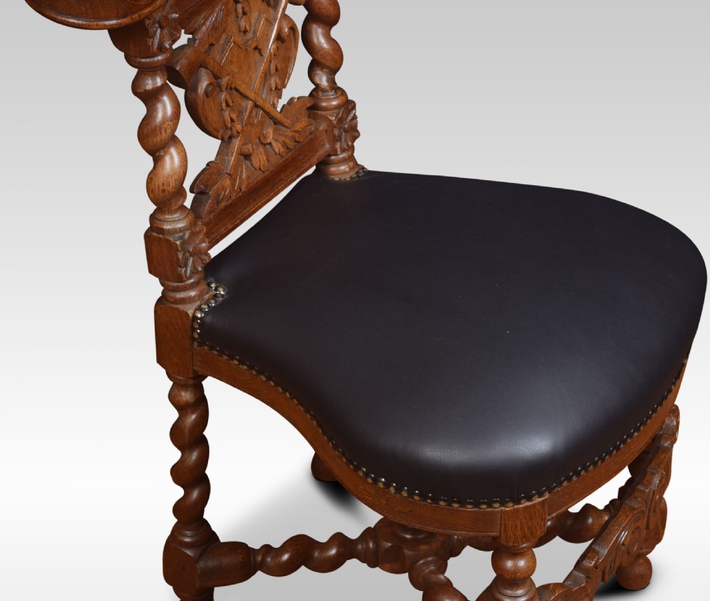 A carved oak side chair with barley twist supports, dark leather padded top rail and seat, and a central coat of arms motif on the backrest. View VI